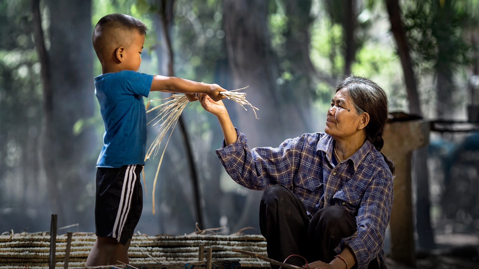 elderly woman and child working with dry grass