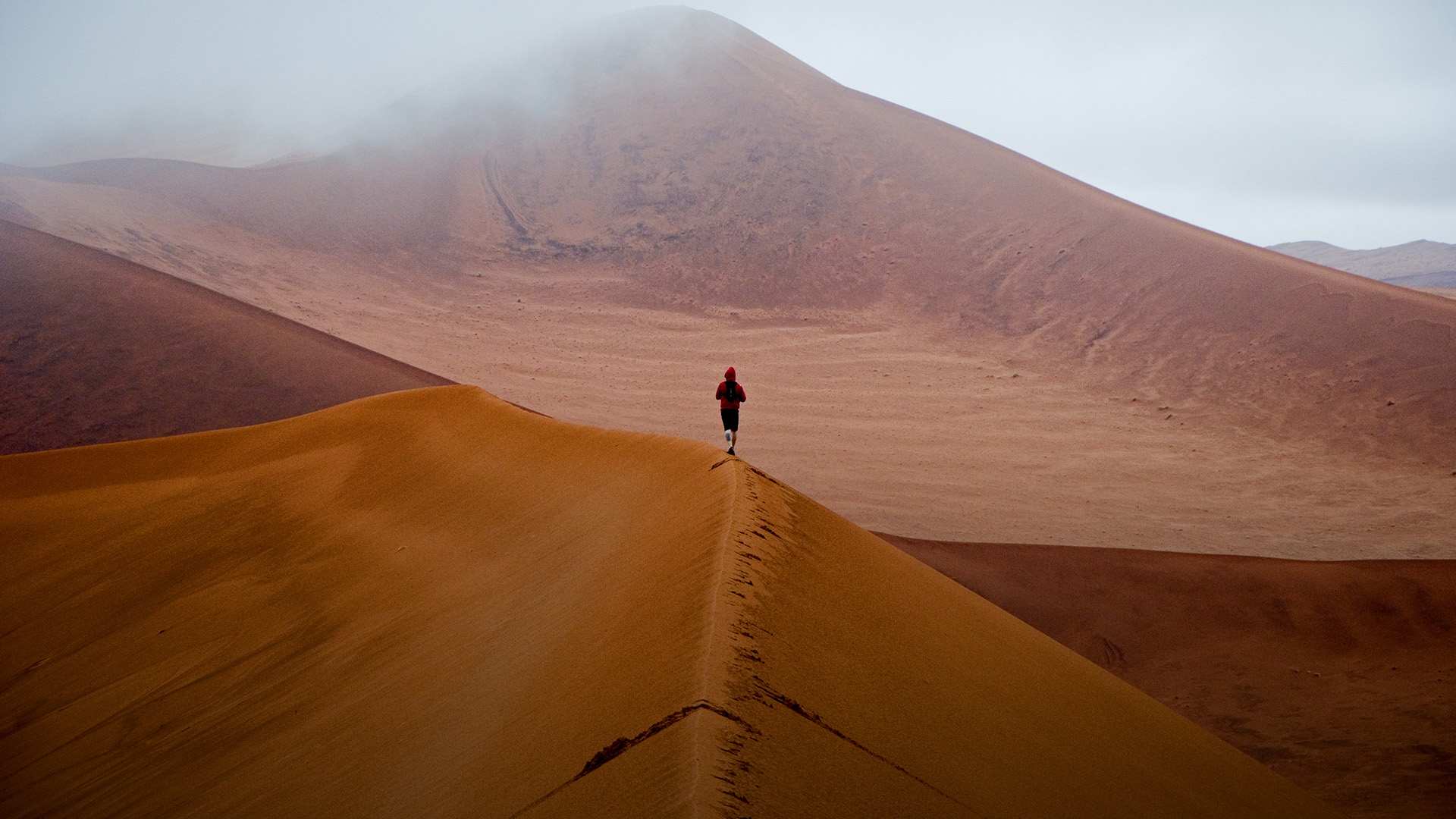 Person walking on desert dunes.